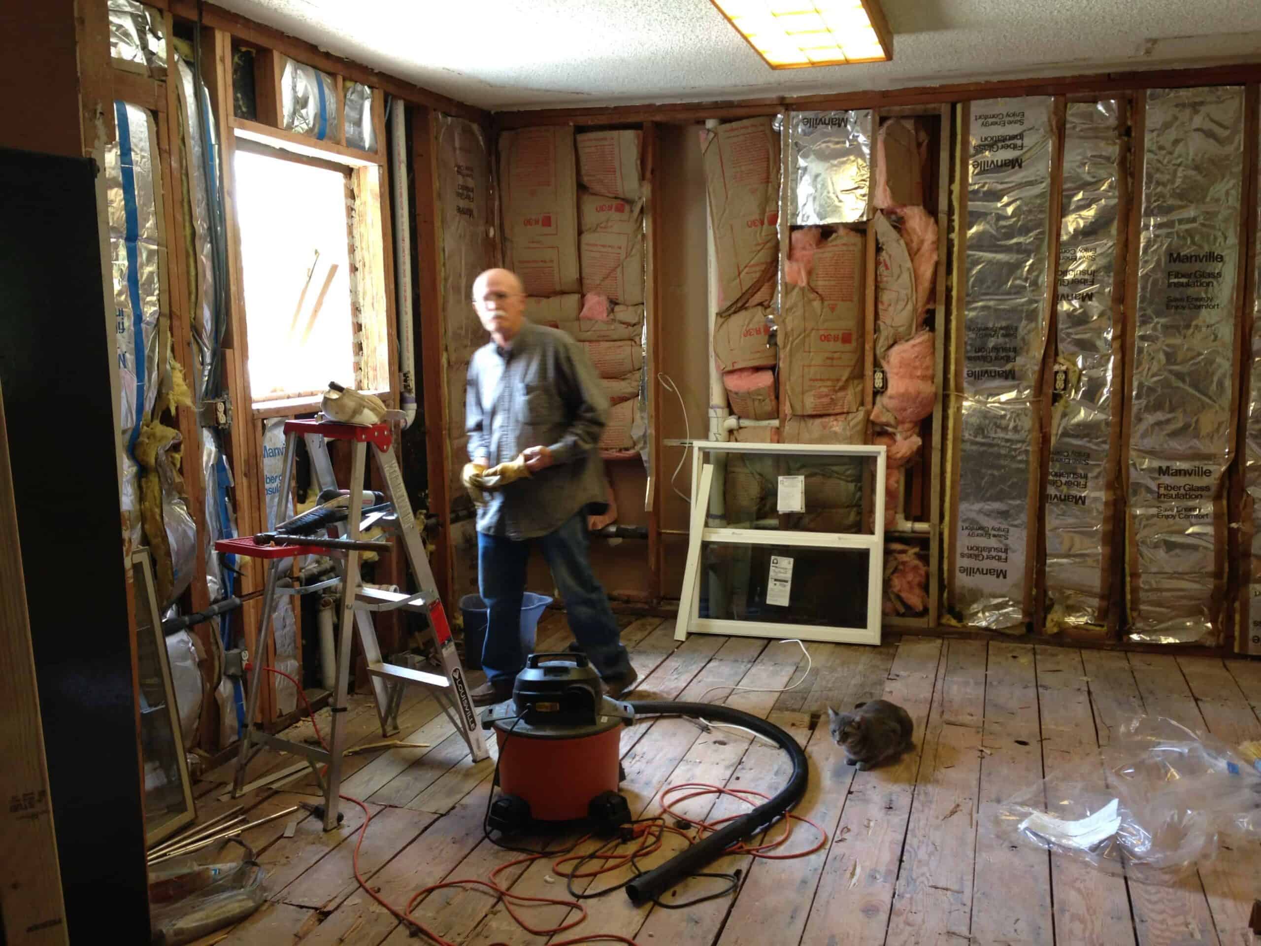 Versatile worker inspecting renovation site amidst construction tools and insulation.