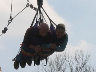Two individuals harnessed together flying in a tandem skydiving jump, demonstrating trust, teamwork, and adventure in the sky.