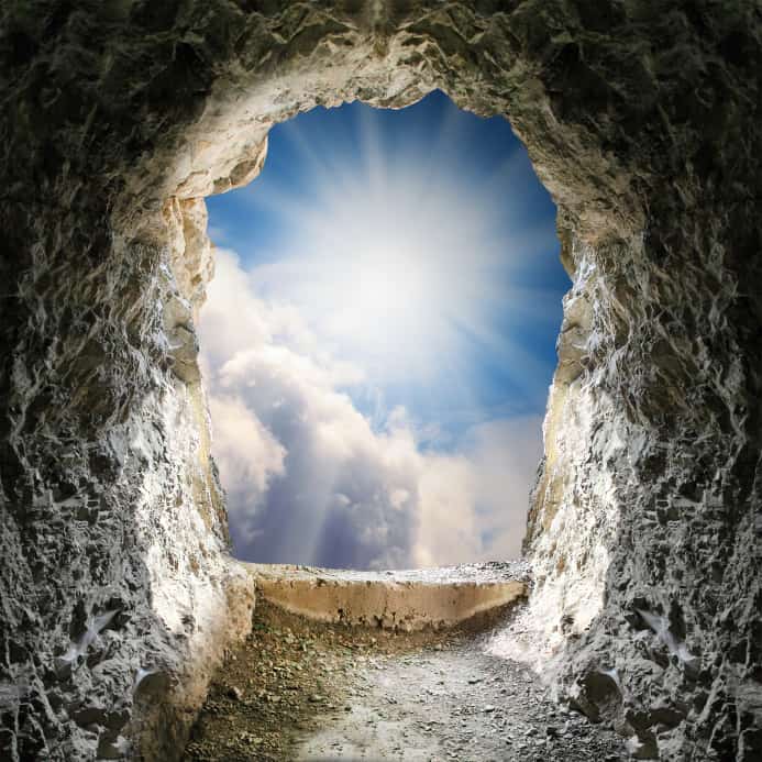 View from inside a cave looking out at a bright sky with clouds and sunlight, symbolizing expanded consciousness and limitless potential.