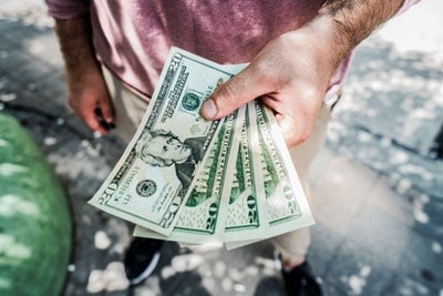 A person holding multiple US dollar bills, symbolizing wealth and financial success, with a focus on mindset and strategies to win the lottery.