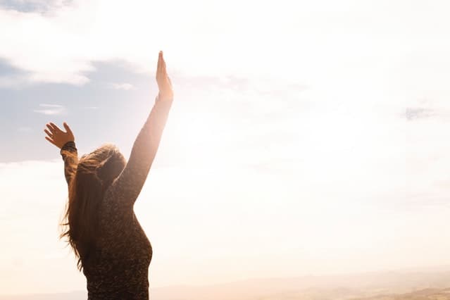 lady raising hands in sunrise